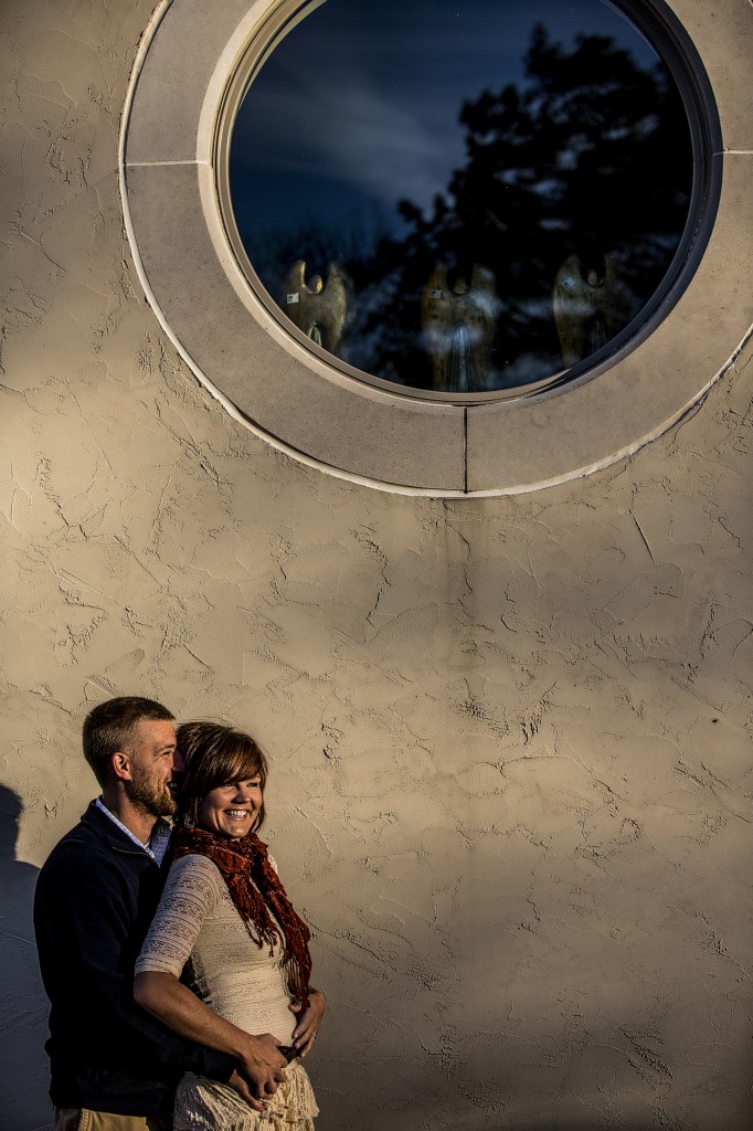 A La Crosse wedding photographer captures a couple posing in front of a round window.
