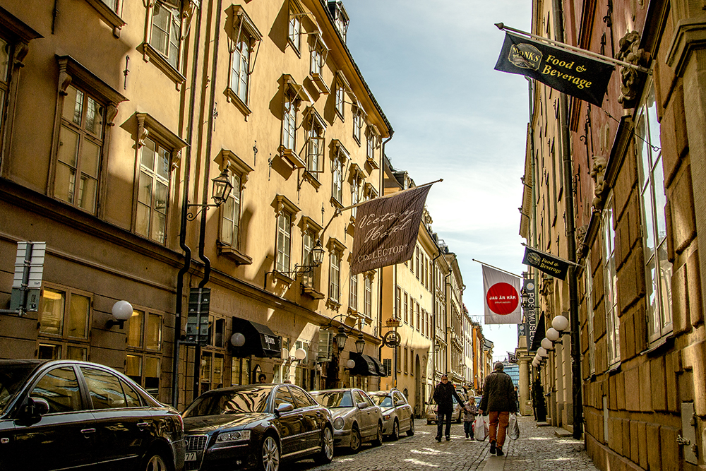 A Stockholm street with cars parked on it captured in photography.
