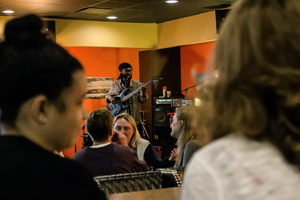 A group of people sitting in Java Vino restaurant watching a musician.
