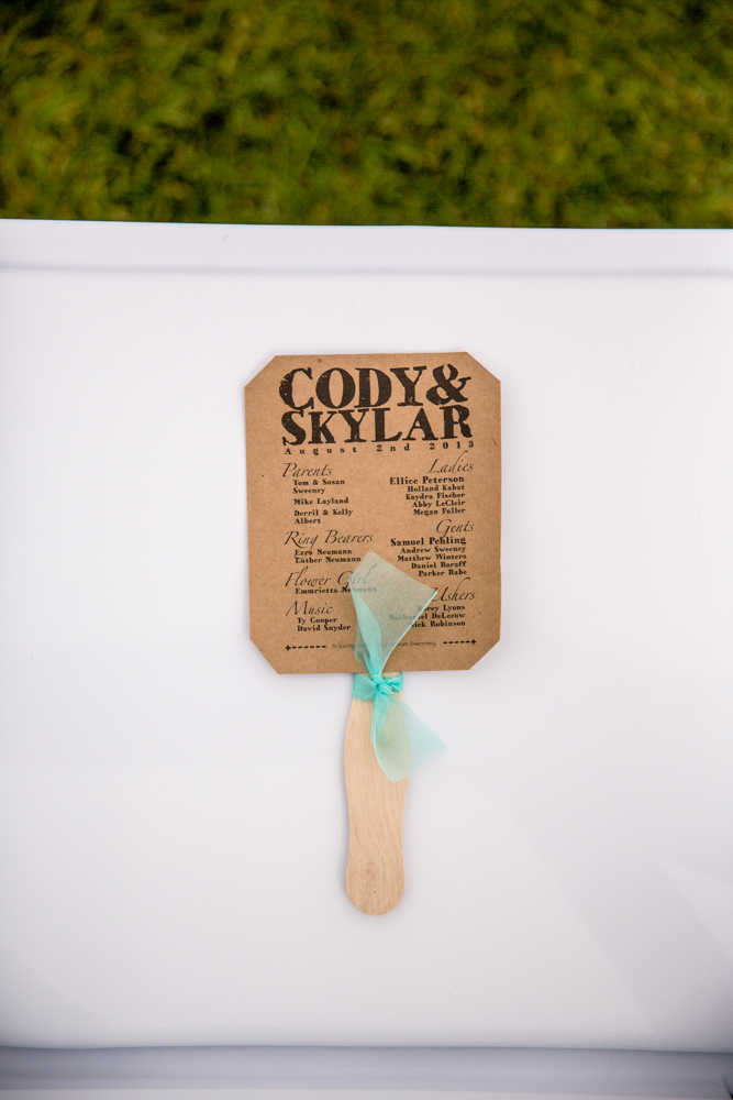 A cute wedding detail featuring a fan adorned with the words "Coyote" and "Skylar".