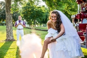A bride and groom standing next to a fire truck.