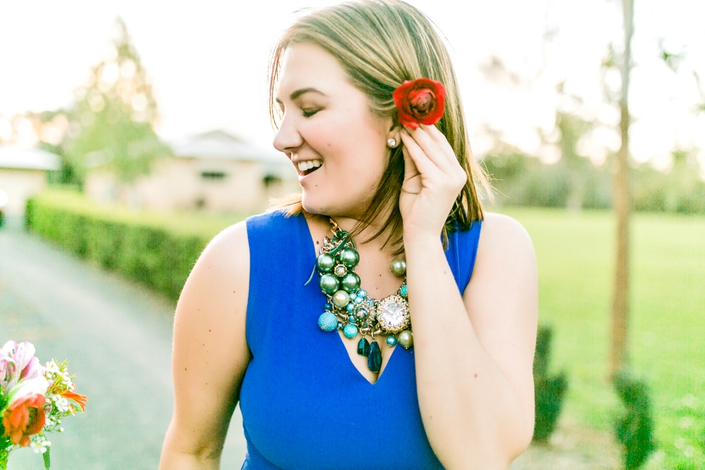 Brisbane Photographer captures a woman in a blue dress with a red flower in her hair.