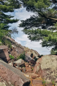 Rocky stone steps ascend through large boulders and pine trees under a partly cloudy sky at Devils Lake.