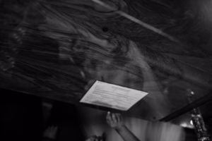 A child’s hand reaches up toward a sheet of paper attached to the underside of a wooden surface with a wavy grain pattern, reminiscent of the elegant woodwork often found in historic Wisconsin Capital Wedding venues.