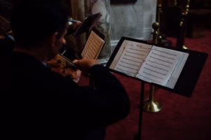A musician plays violin while reading sheet music from a stand in a dimly lit room with red carpeting, adding an elegant touch to a Wisconsin Capital Wedding.