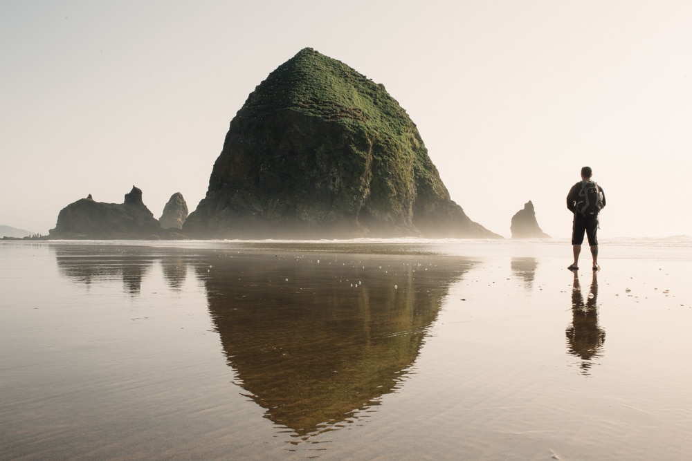 A man at Cannon Beach fascinated by a rock formation.
