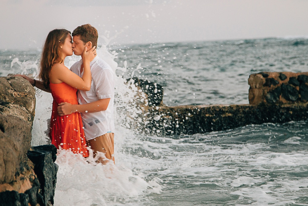 An engaged couple kissing in the ocean captured by an Oahu engagement photographer.