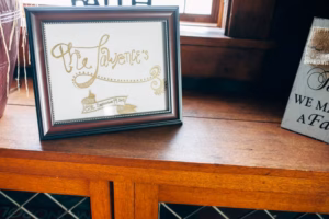 A framed sign reading "The Lawrence's" with "Est. September 14, 2014" sits on a wooden shelf next to a decorative plaque, beautifully captured by an Eau Claire wedding photographer.
