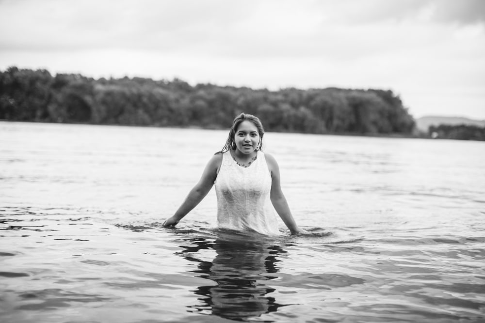 A senior woman in a white dress standing in the water for her photography session.