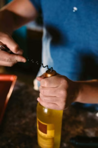 A person uses a corkscrew to open a bottle of white wine on a dark countertop, capturing the moment as an Eau Claire wedding photographer might.