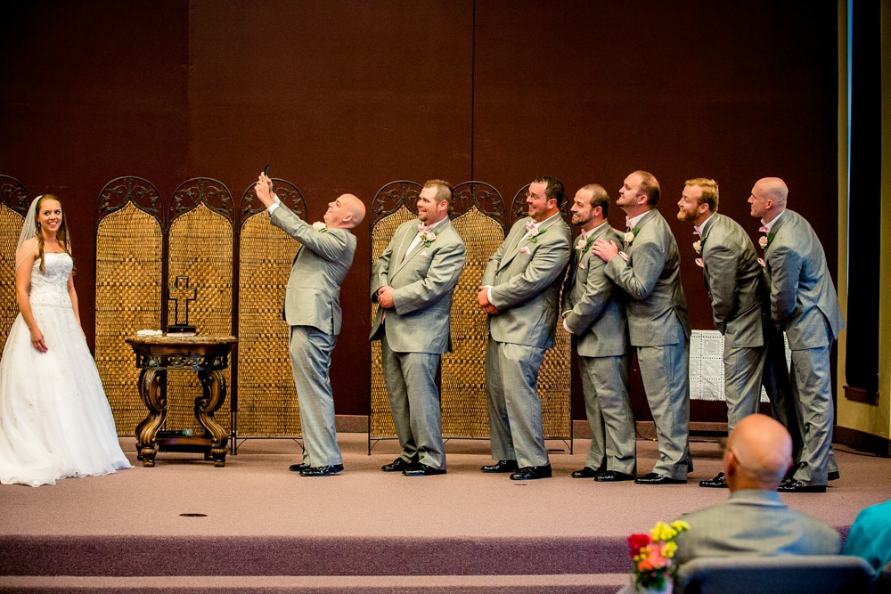 A group of bridesmaids and groomsmen, dressed as Batman characters, taking a picture of each other at a wedding.