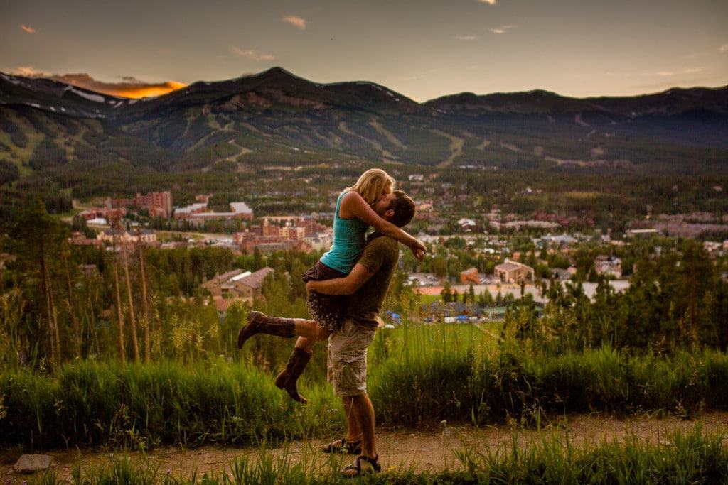 A man and woman hugging in front of a mountain.