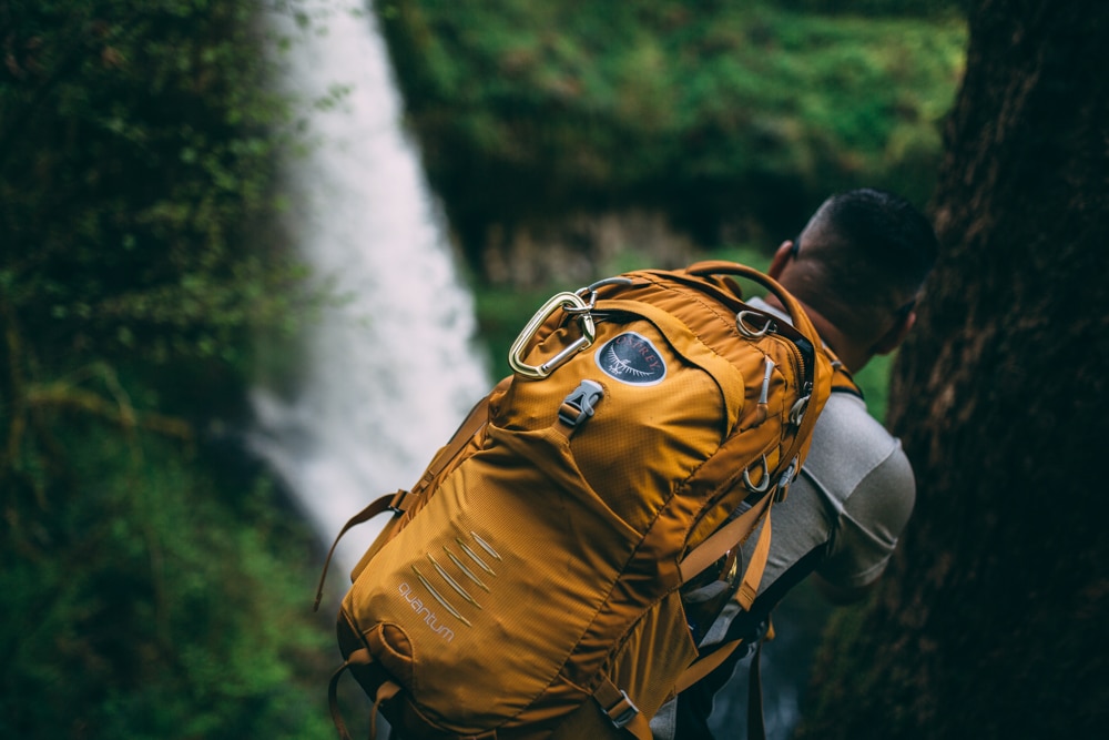 A man hiking the Trail of Ten Falls Loop with a yellow backpack.