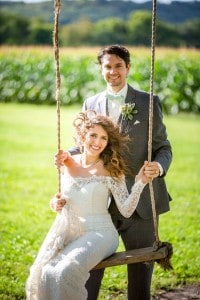 A Rochester bridal party sitting on a swing in a field.