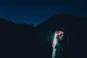 A Norskedalen wedding ceremony with a bride and groom standing in front of a mountain at night.