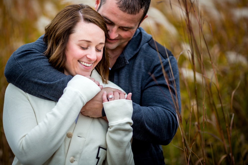 A La Crosse photographer captures a heartfelt moment of a man and woman embracing in tall grass.