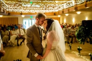 A bride and groom share their first kiss at a Silverthorne, CO wedding under string lights.