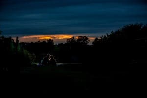 Milwaukee wedding photographer captures a couple sitting on a grassy field at sunset.