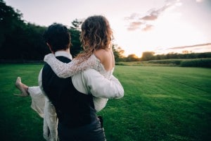 Rochester MN Wedding Photographer captures a couple carrying each other in a field at sunset.