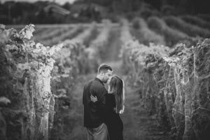 A black and white photo of an engaged couple kissing in a vineyard, captured by a Milwaukee wedding photographer.