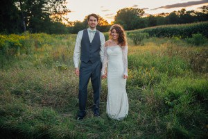 A bride and groom captured by a Rochester MN wedding photographer in a field at sunset.