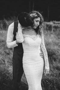 A Rochester MN Wedding Photographer capturing a bride and groom hugging in a field.