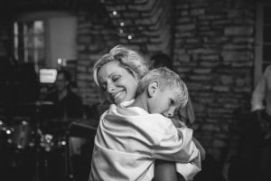 A Rochester MN wedding photographer captures a heartwarming moment of a woman hugging her son on the dance floor.