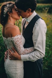A Rochester MN wedding photographer capturing a bride and groom kissing in a field.
