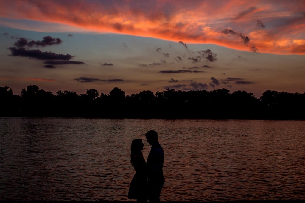 Wedding photographer capturing a couple's silhouette by a lake at sunset in La Crosse.