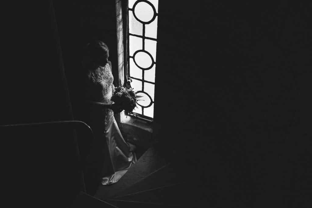 A bride in a dress standing in front of a window at her downtown Minneapolis wedding.