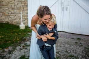 A woman embracing her son in front of the Mayowood Stone Barn.