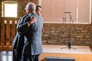 Two men hugging in front of a microphone at the Mayowood Stone Barn.