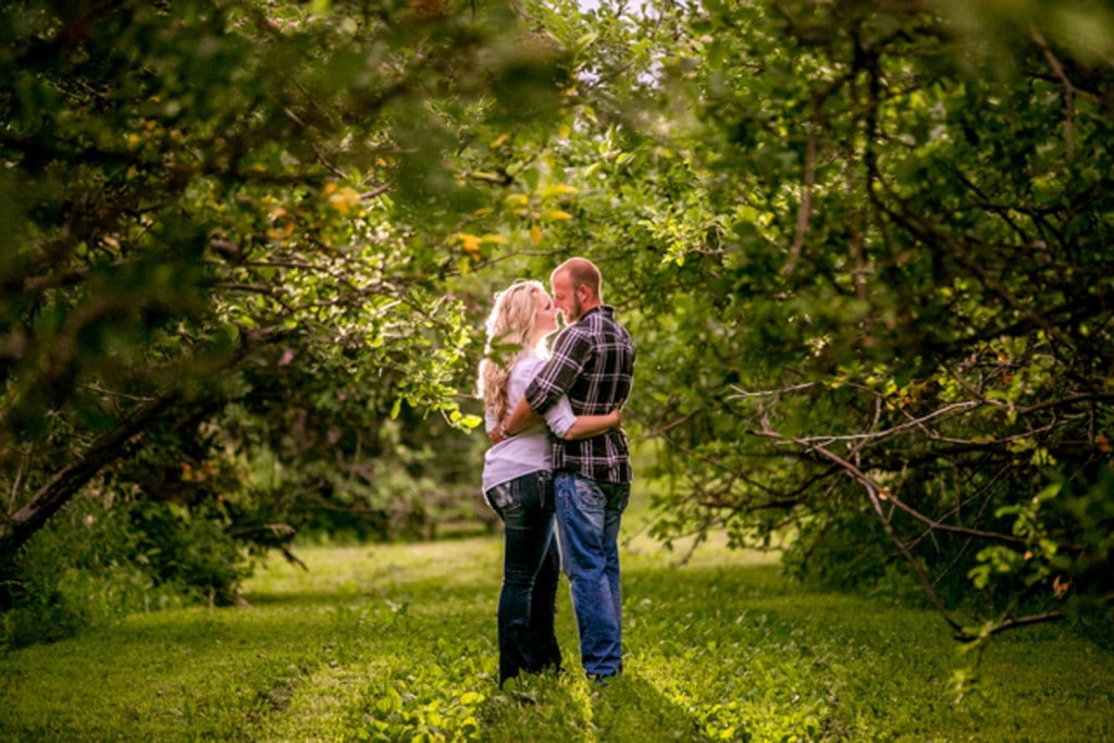 La Crosse wedding photography captures a loving couple embracing amidst an orchard.