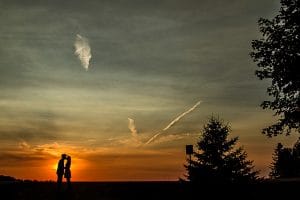 A beautiful silhouette of a couple kissing in front of a sunset captured in wedding photos.