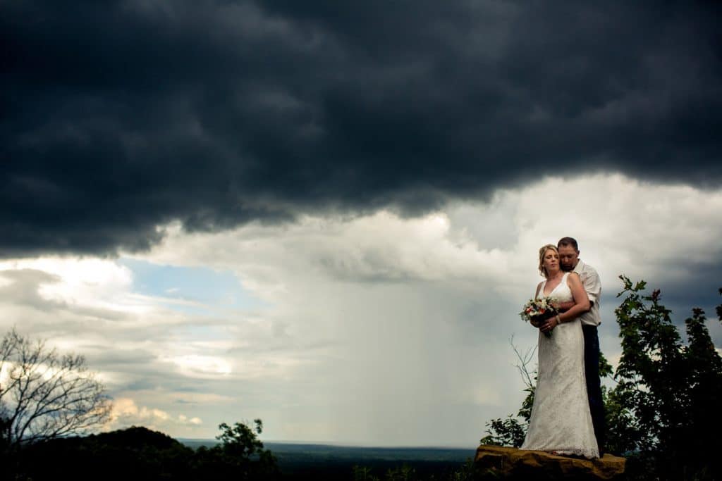 A Burlap and Bells wedding couple posing in front of a stormy sky.