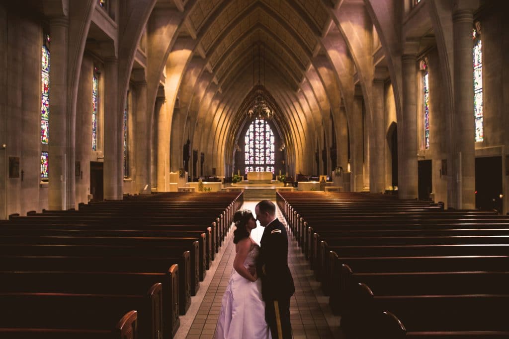 An Army bride and groom standing in the middle of a church for their wedding ceremony.