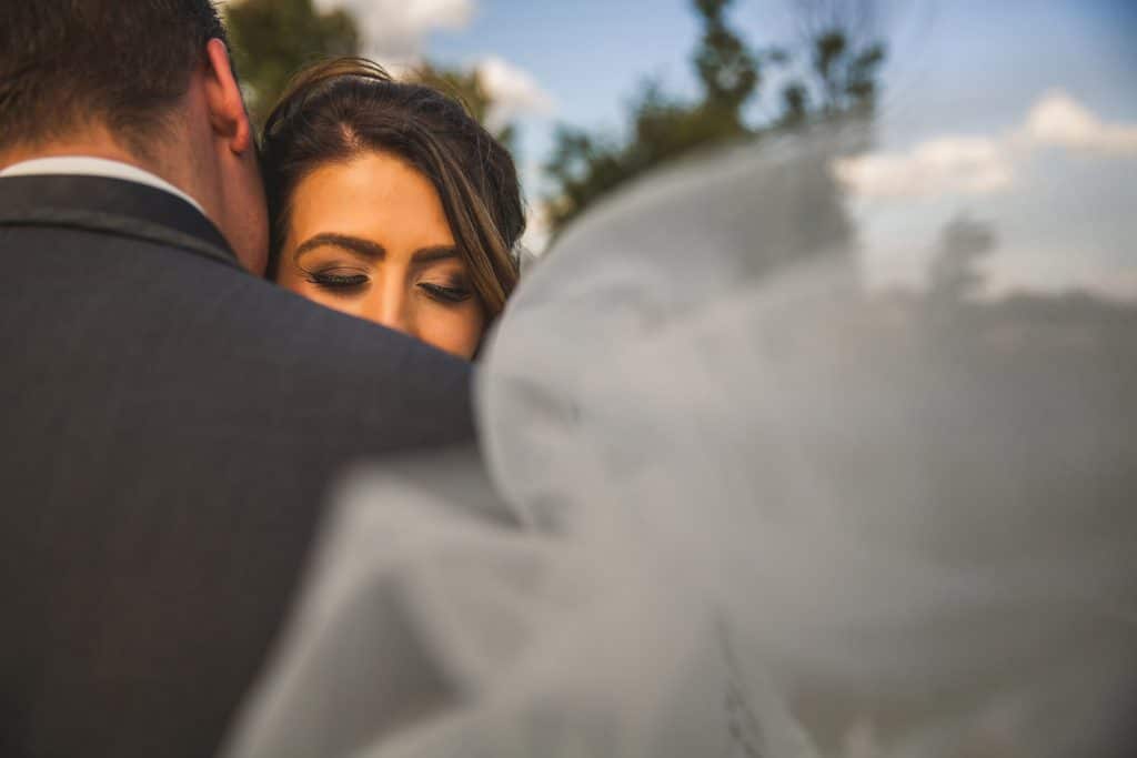 A bride and groom hugging in front of the Eau Claire Golf and Country Club veil.