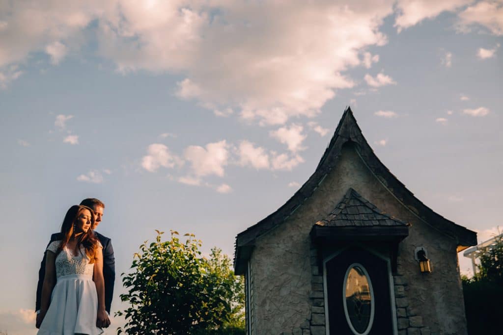 A bride and groom standing in front of a charming cottage.