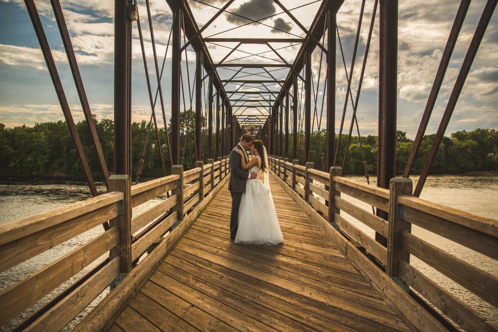 A bride and groom posing on a wooden bridge at the Eau Claire Golf and Country Club.