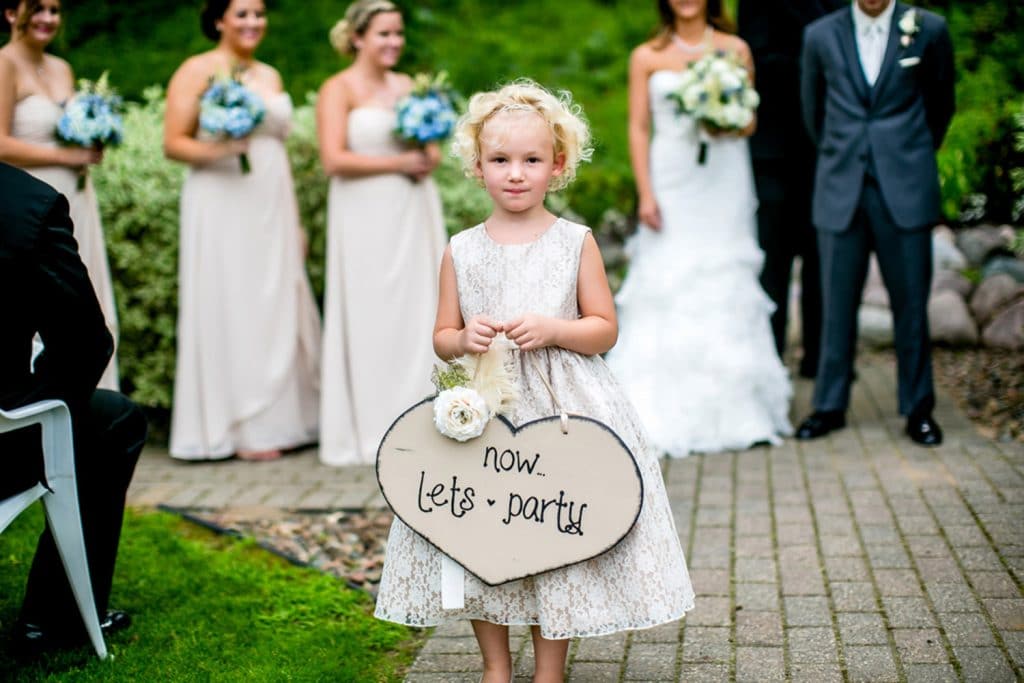 A moody wedding photo capturing a little girl holding a sign that says i love you.