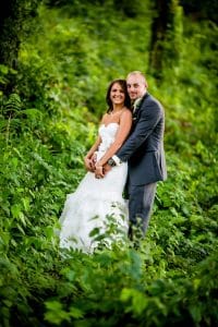 Moody bride and groom posing in the woods.