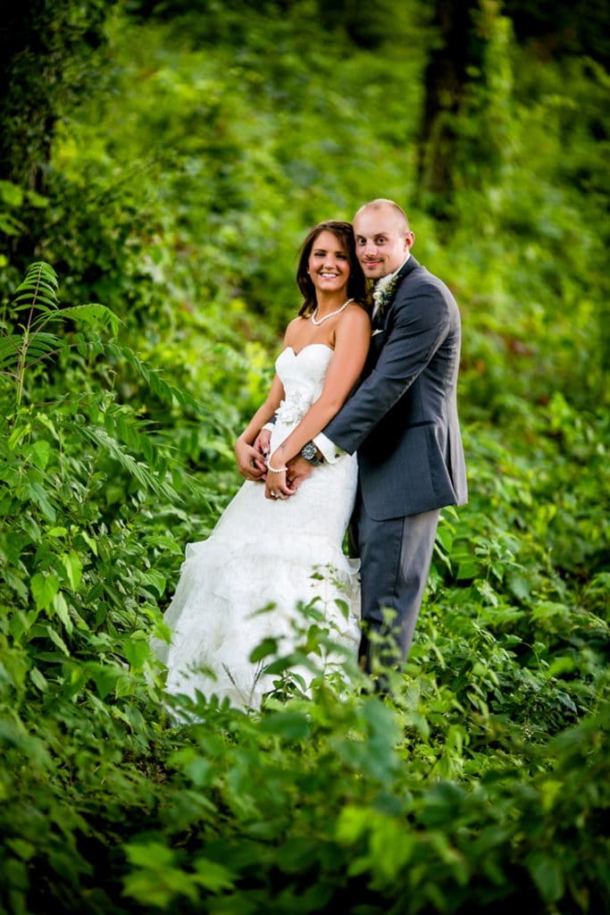 Moody bride and groom posing in the woods.
