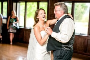 A bride and her father share a heartfelt moment, captured in moody wedding photos.