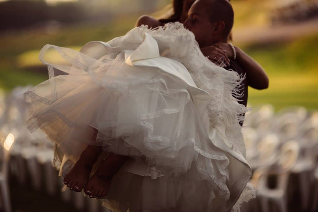 A moody groom carries a bride at their wedding, captured in stunning photos.
