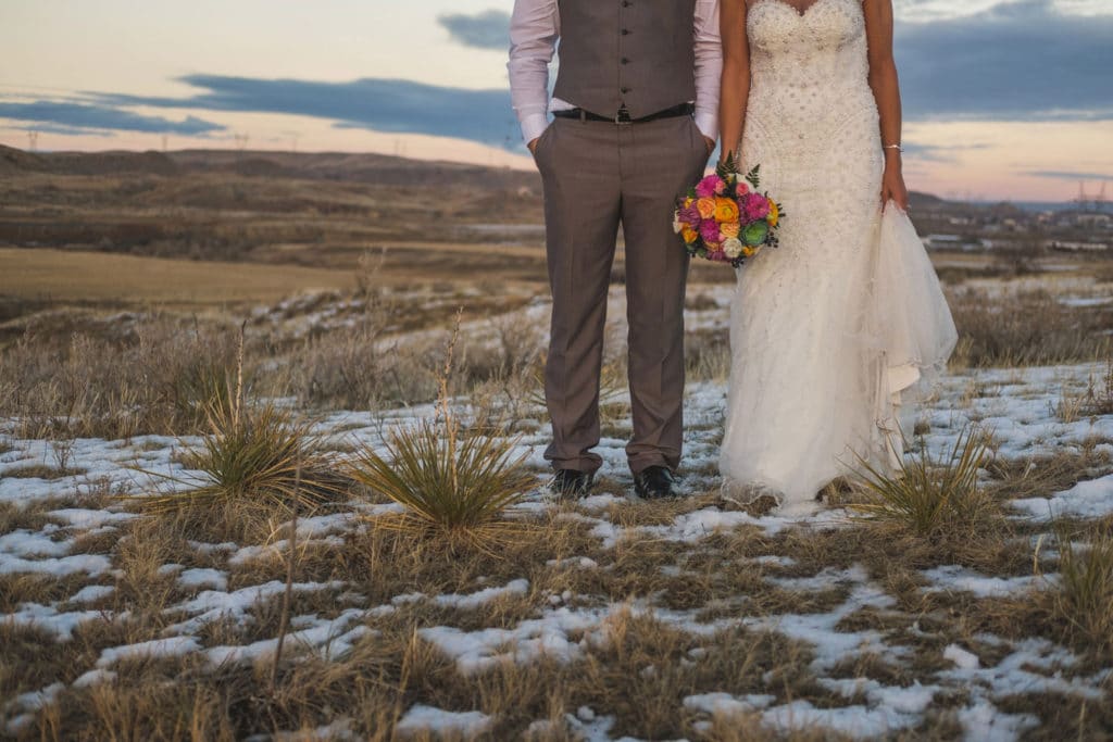 A Montana Wedding Photographer captures a bride and groom standing in a snow-covered field.