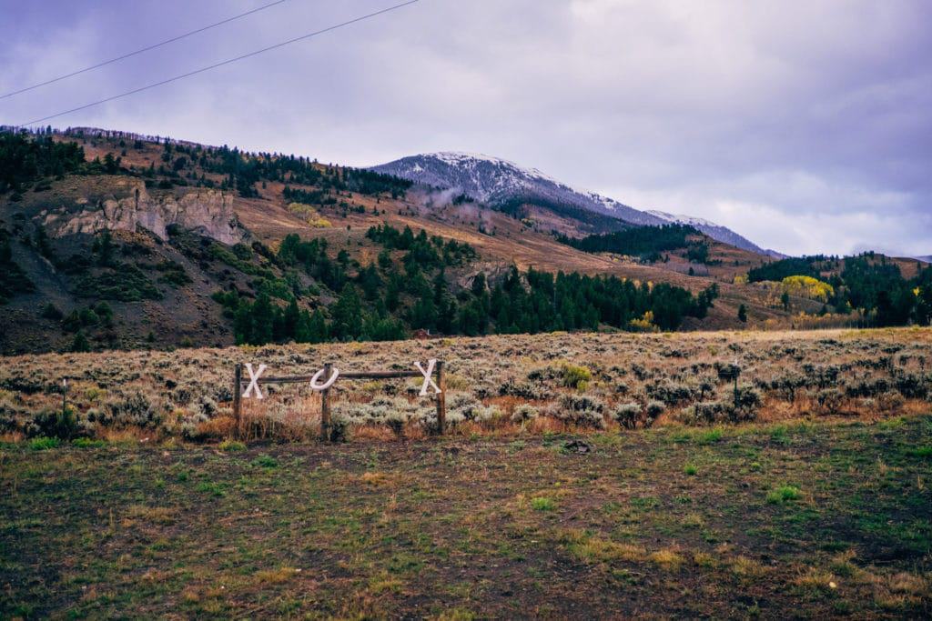 A field with a fence and mountains in the background.