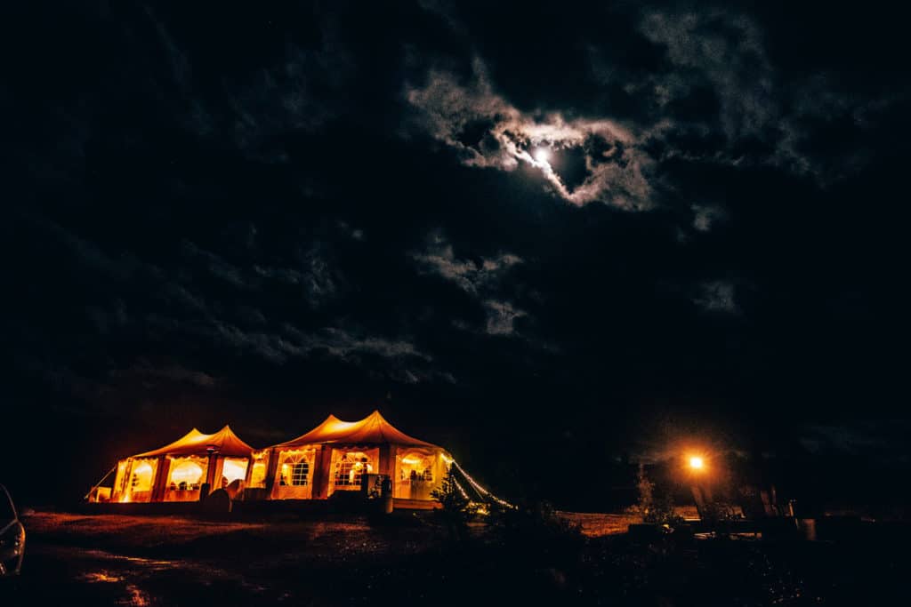 A mesmerizing La Crosse WI wedding photographer captures a beautifully illuminated tent under a full moon.