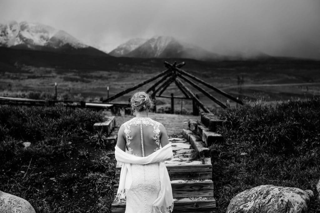 A bride posing on a wooden bridge in La Crosse, WI with scenic mountain views captured by a talented wedding photographer.