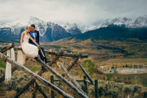 A La Crosse WI Wedding Photographer captures a bride and groom on a wooden bridge with mountains as the picturesque backdrop.