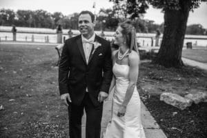 Black and white photo of bride and groom walking down a path.
